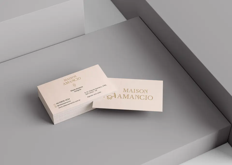 Cartões de visita da Maison Amancio em tom creme, com o logotipo em dourado.
